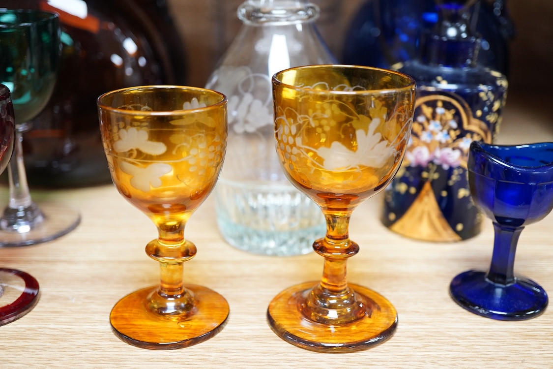 A collection of coloured glass flagons, glasses and bottles etc. (18). Tallest decanter and stopper 25cm high.